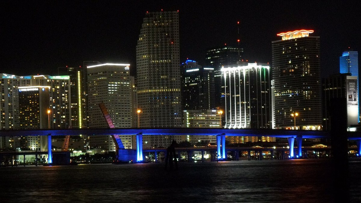 Centro de Miami iluminado à noite, visto da baía, em foto ilustrativa da cidade que inspira Vice City